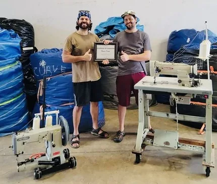 FixMyInflatable students holding their repair certificate next to a Portable Sewing Machine